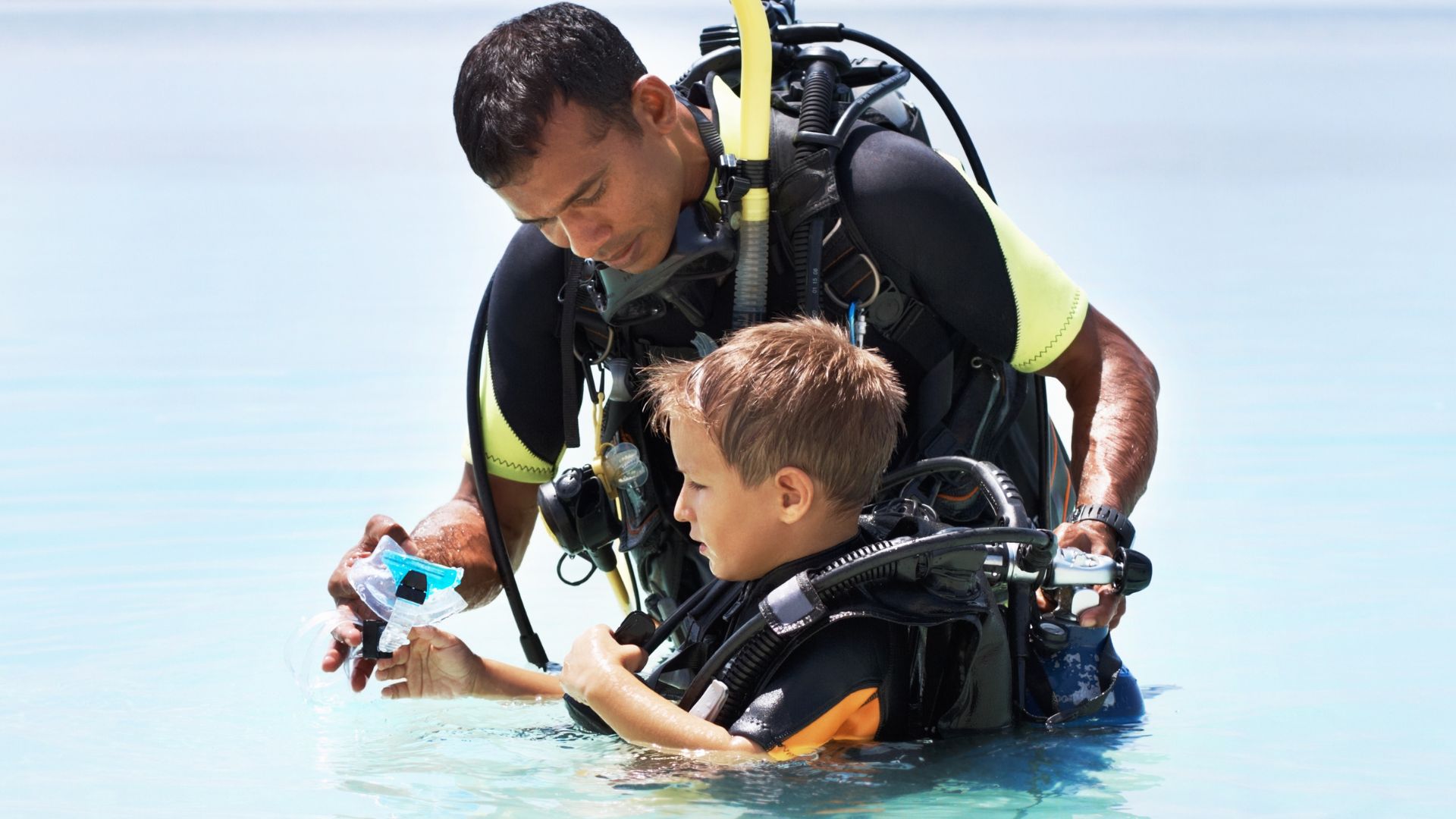 Instructor enseñando buceo a un niño en el mar